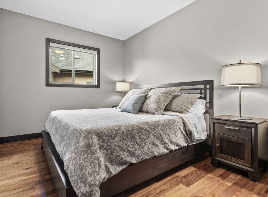 Experience comfort and style in this beautifully appointed bedroom, featuring a plush queen-size bed adorned with elegant bedding and decorative pillows.