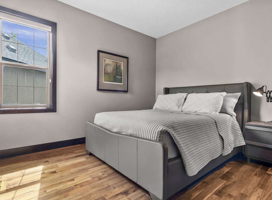 Experience comfort and style in this beautifully appointed bedroom, featuring a plush grey upholstered bed and a coordinating nightstand with a modern lamp.