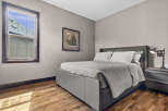 Experience comfort and style in this beautifully appointed bedroom, featuring a plush grey upholstered bed and a coordinating nightstand with a modern lamp.