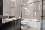 This modern bathroom features a sleek vanity with a granite countertop and a stylish mosaic backsplash.