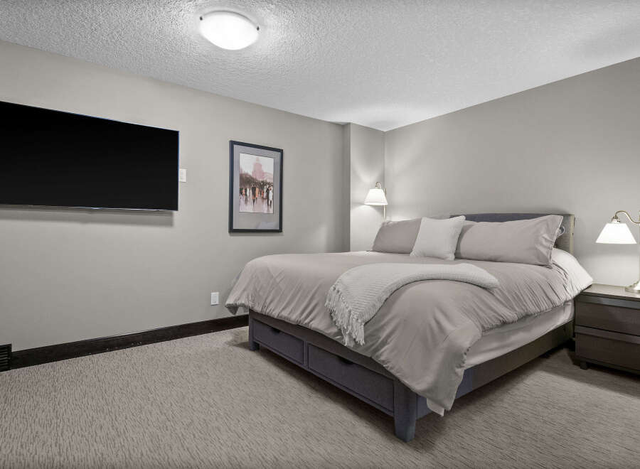 Experience ultimate comfort in this inviting bedroom, featuring a plush king-size bed adorned with soft, neutral linens and a cozy throw blanket.