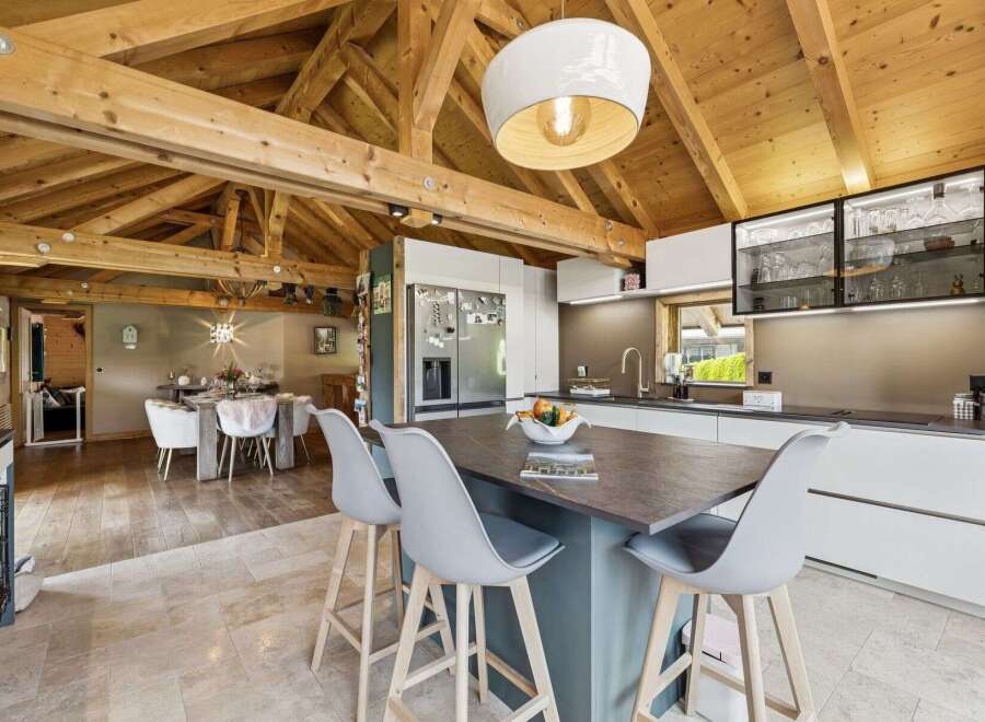 Experience rustic charm and modern luxury in this stunning open-plan living space, featuring exposed wooden beams and a spacious kitchen island perfect for entertaining.