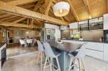 Experience rustic charm and modern luxury in this stunning open-plan living space, featuring exposed wooden beams and a spacious kitchen island perfect for entertaining.