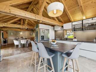 Experience rustic charm and modern luxury in this stunning open-plan living space, featuring exposed wooden beams and a spacious kitchen island perfect for entertaining.