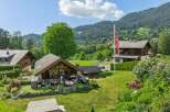 Experience serene mountain living in this charming property featuring a spacious wooden chalet with a large glass facade, perfect for enjoying the picturesque views.
