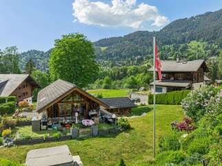 Experience serene mountain living in this charming property featuring a spacious wooden chalet with a large glass facade, perfect for enjoying the picturesque views.