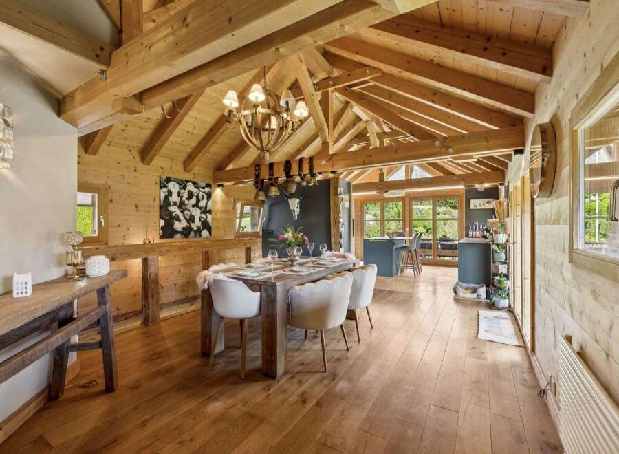 Experience rustic charm in this beautifully appointed dining area, featuring exposed wooden beams and a cozy chandelier.
