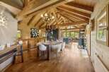 Experience rustic charm in this beautifully appointed dining area, featuring exposed wooden beams and a cozy chandelier.