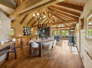 Experience rustic charm in this beautifully appointed dining area, featuring exposed wooden beams and a cozy chandelier.