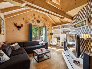 Experience cozy living in this charming wooden cabin-style living room, featuring a spacious sectional sofa perfect for relaxation.