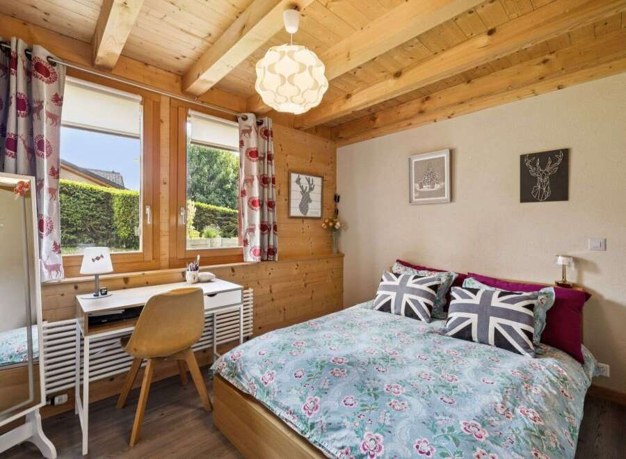 Charming wooden cabin bedroom featuring a cozy bed with Union Jack pillows and floral bedding.