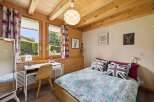 Charming wooden cabin bedroom featuring a cozy bed with Union Jack pillows and floral bedding.