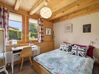 Charming wooden cabin bedroom featuring a cozy bed with Union Jack pillows and floral bedding.