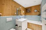 Experience rustic charm in this bathroom featuring warm, natural wood paneling and a soothing light blue tiled wainscoting.
