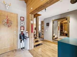 Step into a charming entryway featuring a rustic wooden door adorned with a festive wreath and a unique bull skull decoration.