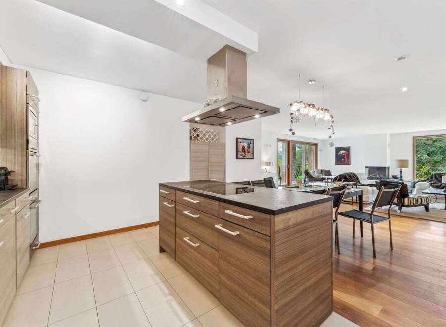 Experience modern living in this open-concept home, featuring a sleek kitchen island with a built-in cooktop and ample storage.