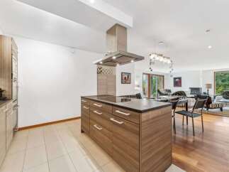 Experience modern living in this open-concept home, featuring a sleek kitchen island with a built-in cooktop and ample storage.