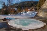 Experience ultimate relaxation in this luxurious outdoor hot tub, perfectly situated on a wooden deck with stunning mountain views.