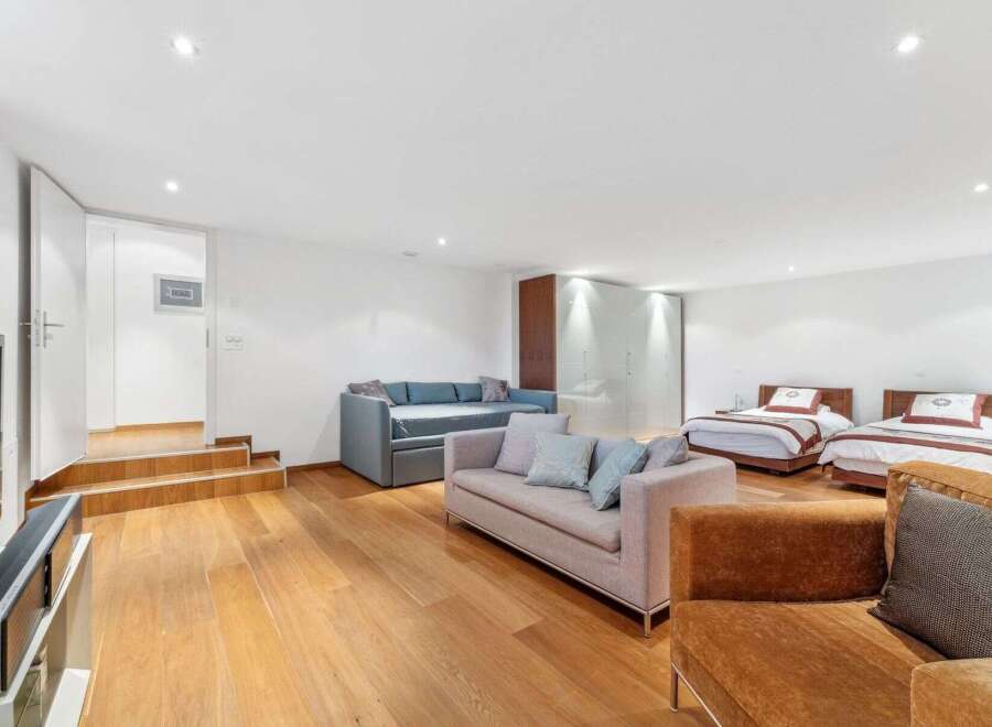 This spacious room offers a versatile living and sleeping area, featuring two comfortable sofas and two twin beds perfect for guests.