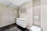 Experience modern luxury in this sleek bathroom featuring a floating vanity with ample storage and a spacious glass-enclosed shower.