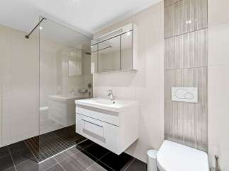 Experience modern luxury in this sleek bathroom featuring a floating vanity with ample storage and a spacious glass-enclosed shower.