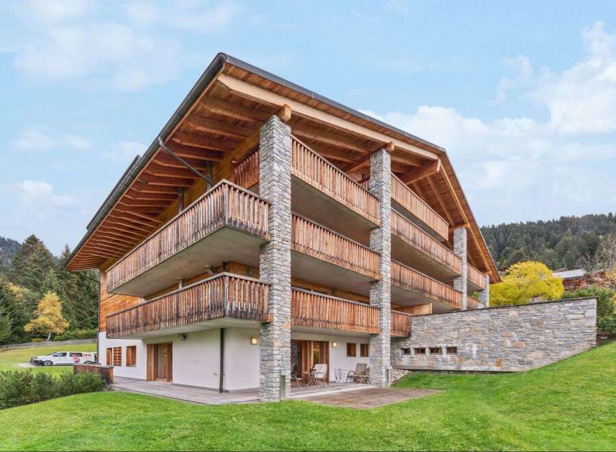 Experience luxury mountain living in this stunning chalet-style property, featuring expansive wooden balconies and natural stone accents.