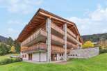 Experience luxury mountain living in this stunning chalet-style property, featuring expansive wooden balconies and natural stone accents.