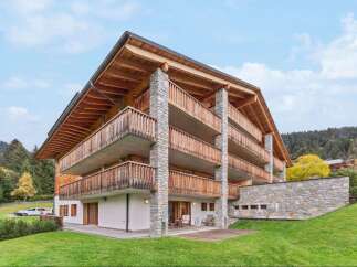 Experience luxury mountain living in this stunning chalet-style property, featuring expansive wooden balconies and natural stone accents.
