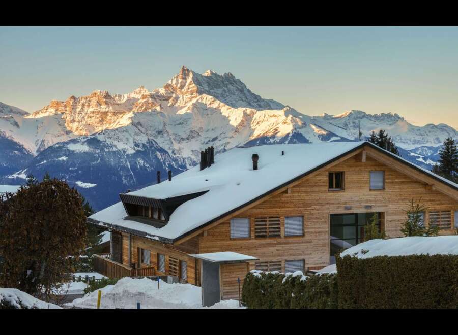 Experience the ultimate alpine retreat in this stunning wooden chalet, perfectly situated against a backdrop of majestic snow-capped mountains.