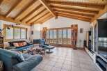 Experience breathtaking mountain views from this stunning living room, featuring a vaulted wood-beamed ceiling and expansive glass doors.