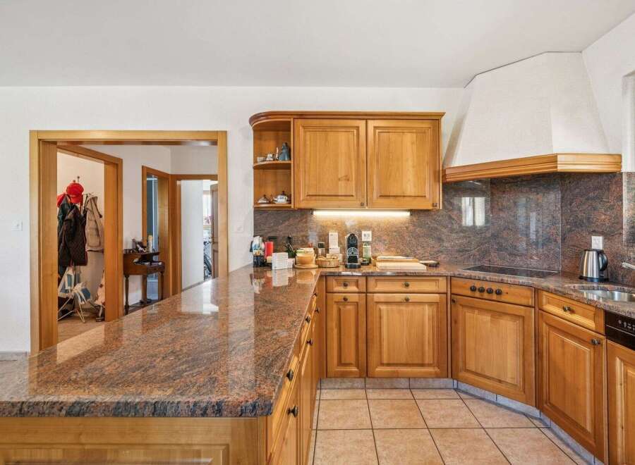 Discover this charming kitchen featuring warm wooden cabinetry and a stunning granite countertop that extends into a breakfast bar.
