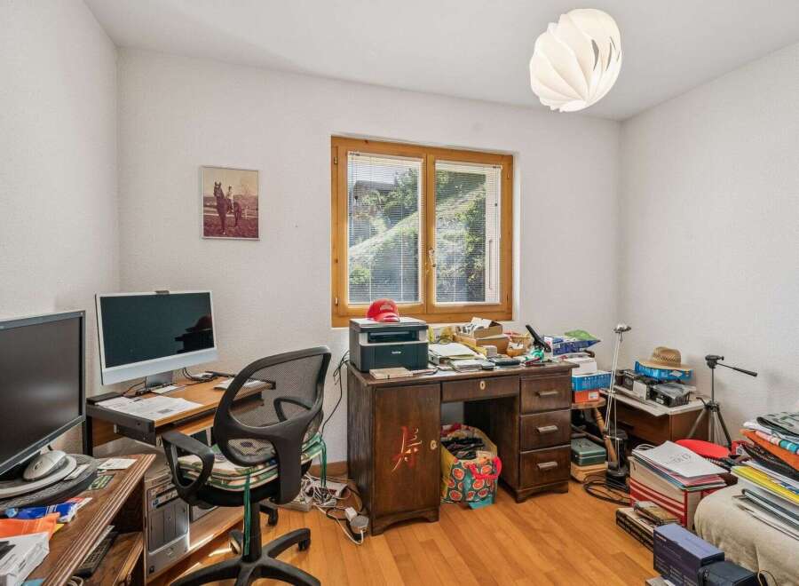 This home office features a spacious wooden desk equipped with a printer and multiple monitors, perfect for productivity.