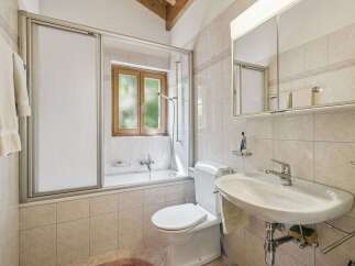 This charming bathroom features a bathtub with a sliding glass door, perfect for a relaxing soak.