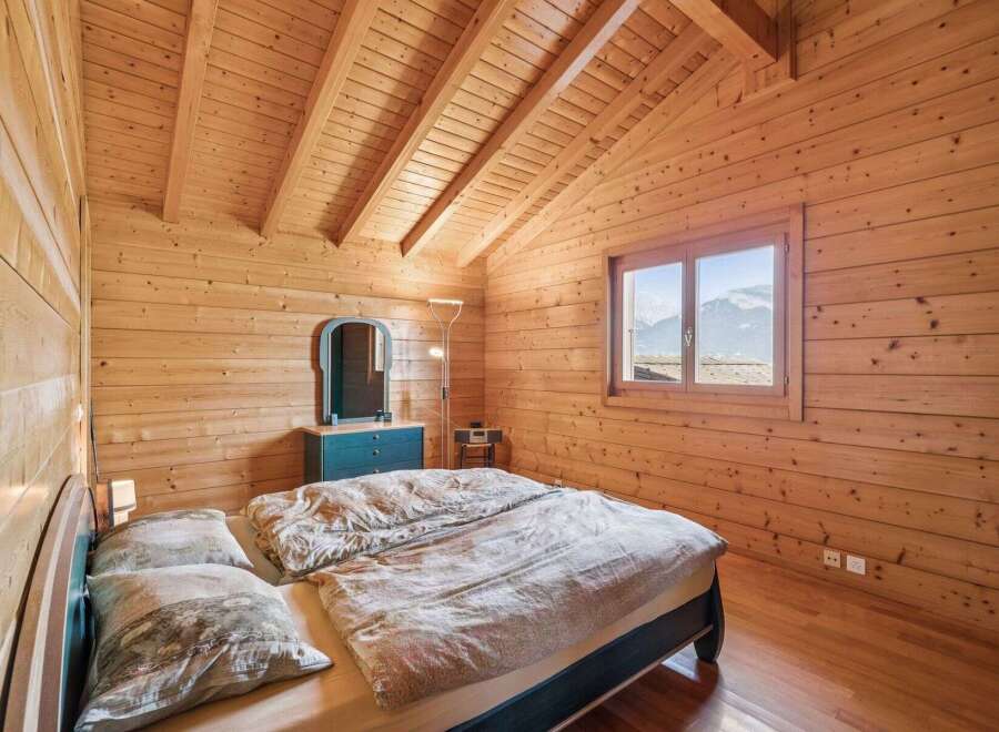 Experience cozy mountain living in this charming wooden bedroom, featuring a comfortable bed adorned with patterned bedding and plush pillows.