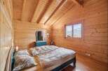 Experience cozy mountain living in this charming wooden bedroom, featuring a comfortable bed adorned with patterned bedding and plush pillows.
