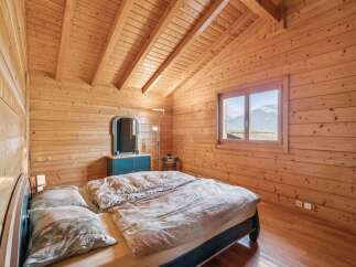 Experience cozy mountain living in this charming wooden bedroom, featuring a comfortable bed adorned with patterned bedding and plush pillows.