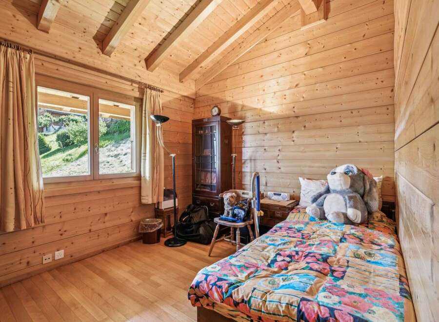Experience cozy living in this charming wooden cabin bedroom, featuring a comfortable bed adorned with a vibrant floral comforter.