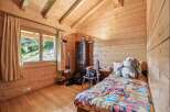 Experience cozy living in this charming wooden cabin bedroom, featuring a comfortable bed adorned with a vibrant floral comforter.