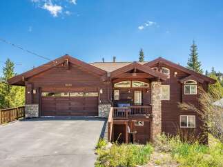 Nestled amidst lush greenery and tall pine trees, this stunning wooden home offers a serene mountain retreat.