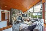 Experience breathtaking mountain views from this stunning living room, featuring a magnificent stone fireplace and a vaulted wood-paneled ceiling.