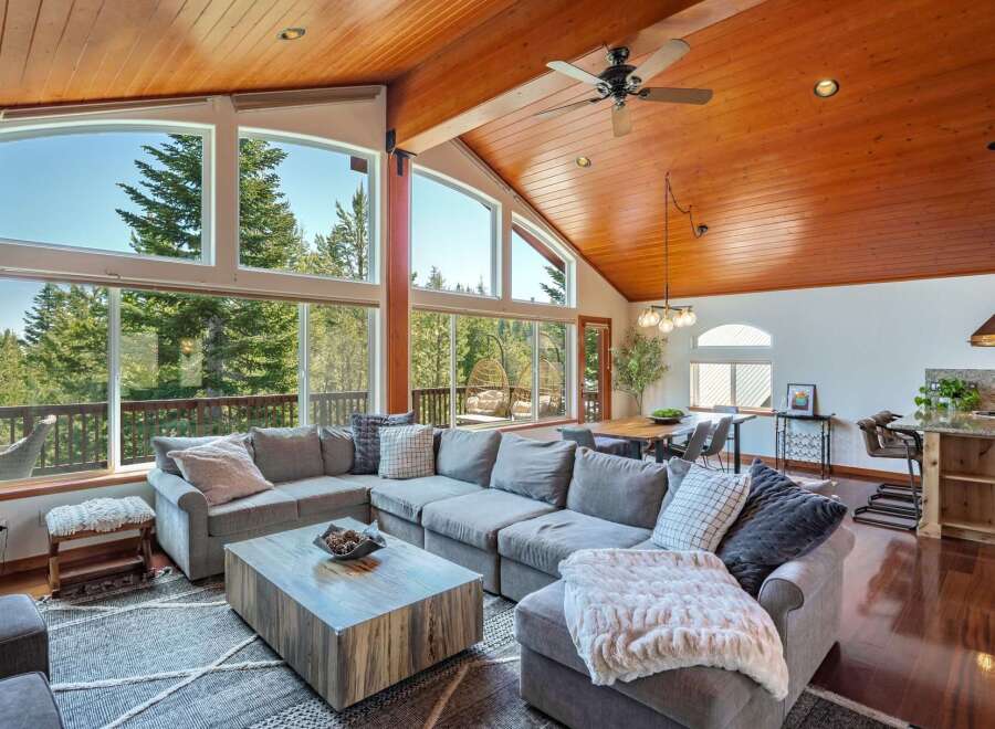 Experience breathtaking mountain views from this stunning living room, featuring a massive sectional sofa and a rustic wood coffee table.