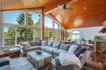 Experience breathtaking mountain views from this stunning living room, featuring a massive sectional sofa and a rustic wood coffee table.