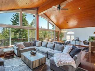 Experience breathtaking mountain views from this stunning living room, featuring a massive sectional sofa and a rustic wood coffee table.