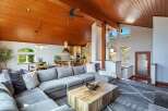 Experience rustic charm and modern comfort in this stunning open-concept living space, featuring a soaring wood-paneled ceiling and a cozy sectional sofa perfect for gatherings.