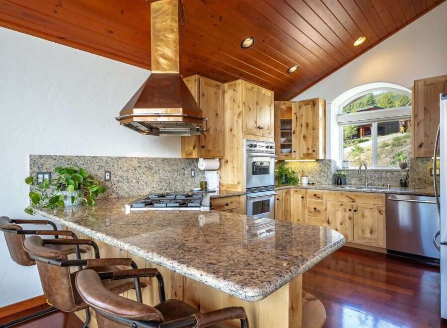 Experience rustic charm in this stunning kitchen featuring warm wood cabinetry and a vaulted wood-paneled ceiling.