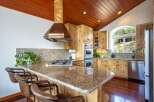 Experience rustic charm in this stunning kitchen featuring warm wood cabinetry and a vaulted wood-paneled ceiling.