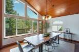 Experience breathtaking views from this stunning dining room, featuring a live-edge wood table and large windows that open to a private balcony surrounded by lush trees.