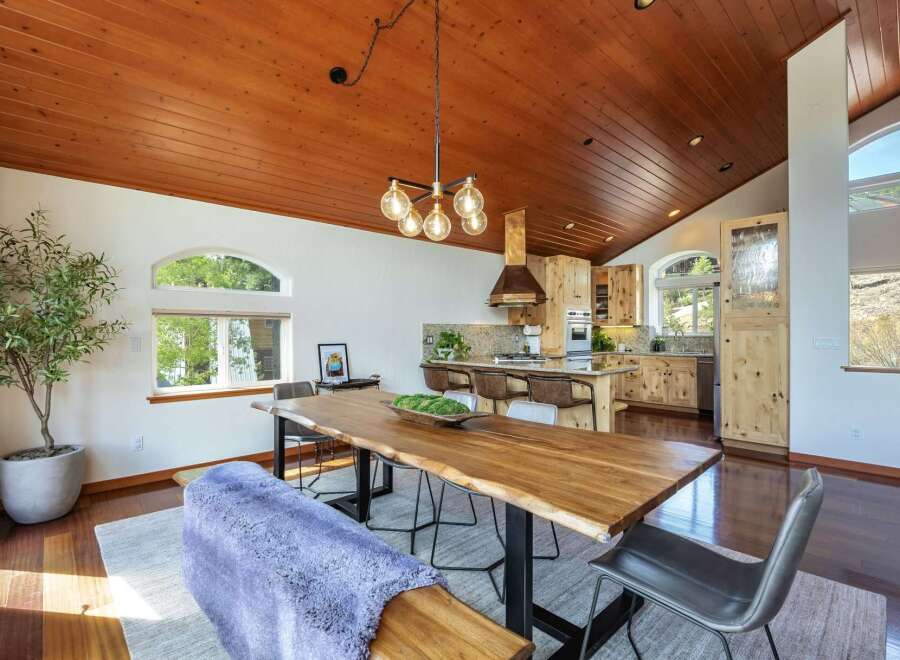 Experience rustic charm and modern comfort in this open-concept dining and kitchen area, featuring a stunning live-edge dining table and a spacious island perfect for entertaining.