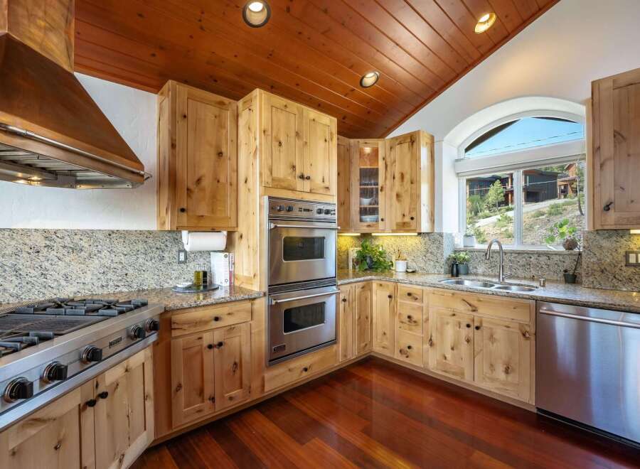 Experience rustic charm in this beautifully appointed kitchen, featuring warm knotty pine cabinetry and a stunning granite countertop.
