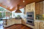 Experience rustic charm and modern convenience in this stunning kitchen, featuring a vaulted wood-paneled ceiling and a striking copper range hood.